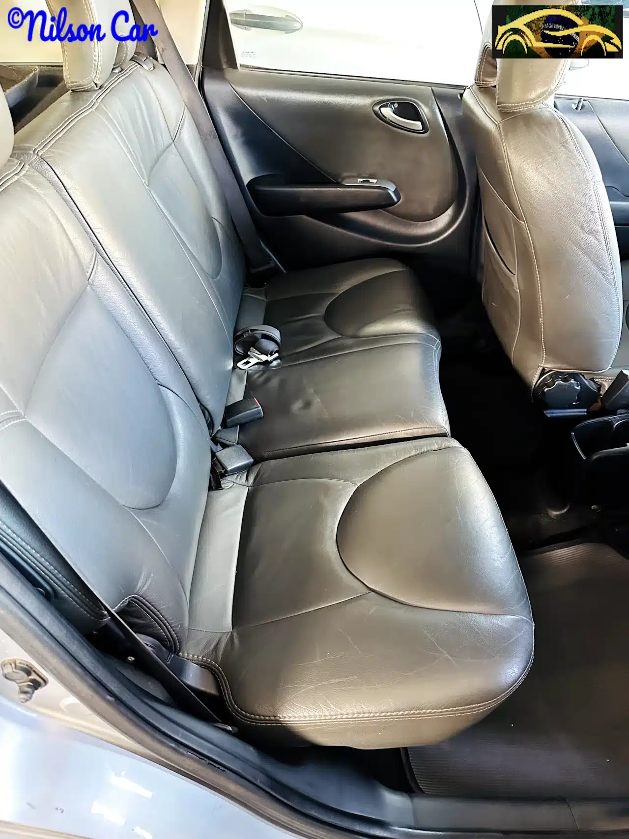 2008 Honda Fit EX 15 Prata - rear_seat-WM - Nilson Car Back seat of a car with black leather upholstery and visible seat belts and headrests.