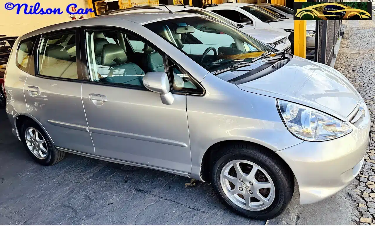 2008 Honda Fit EX 15 Prata - side-WM - Nilson Car Silver Honda minivan parked at a dealership with other cars in the background, side view visible.