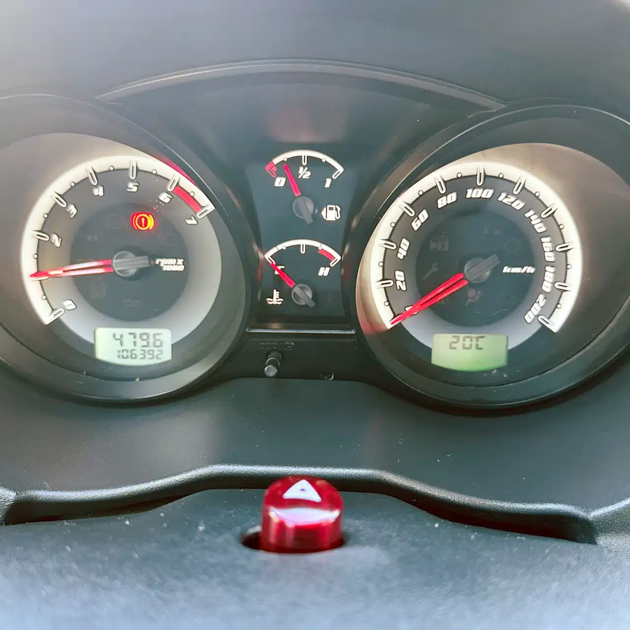 2013 Ford Fiesta Sedan 16 M Flex Branco - speedo - Nilson Car Dashboard of a car showing speedometer, tachometer, fuel gauge, and warning lights; central screens display mileage and temps, with a red hazard icon lit on the left.