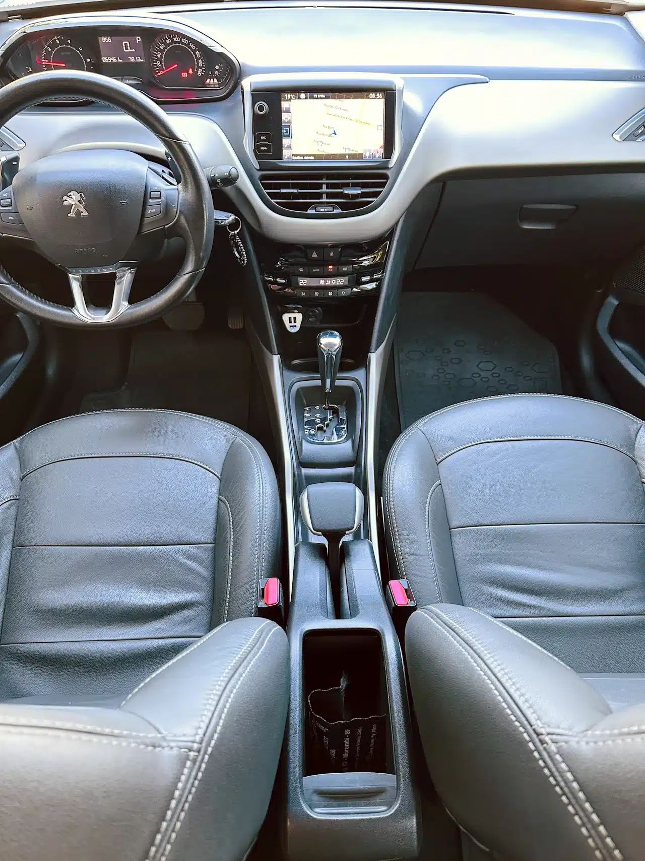 2016 PEUGEOT 2008 16 ALLURE BRANCA - dash - Nilson Car Front interior of a car from rear seats: steering wheel, center touchscreen, gear lever, and gray leather seats.