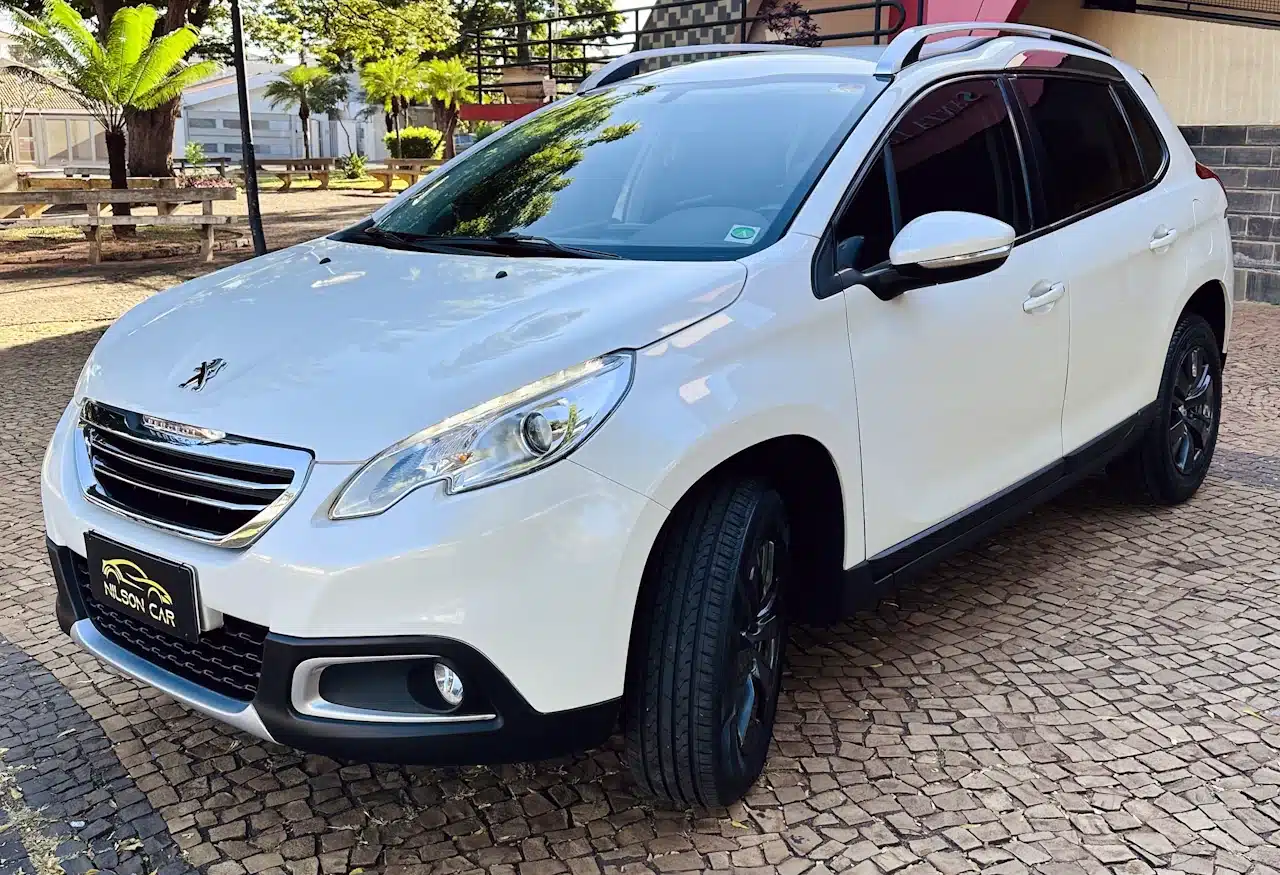 2016 PEUGEOT 2008 16 ALLURE BRANCA - front_side2 - Nilson Car Front-left view of a white Peugeot SUV parked on a cobblestone driveway with trees in the background.