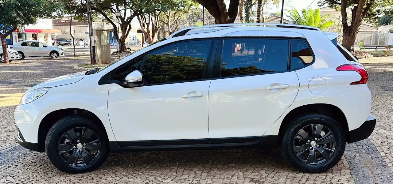 2016 PEUGEOT 2008 16 ALLURE BRANCA - side - Nilson Car Side profile of a white compact SUV with black wheels parked on a cobblestone street, trees in the background