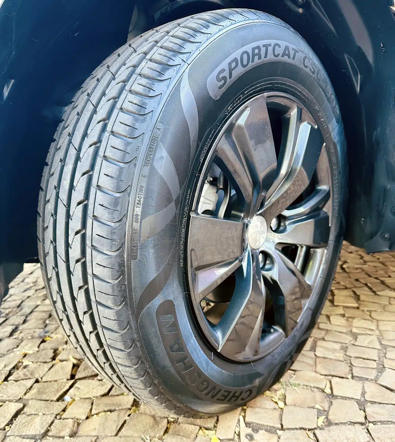 2016 PEUGEOT 2008 16 ALLURE BRANCA - tire - Nilson Car Close-up of a car tire mounted on a dark alloy wheel, showing detailed tread and sidewall text (SPORTCAT).