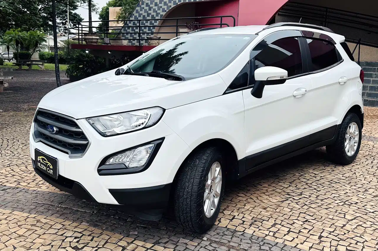 2020-21-Ford-Ecosport-SE-1_5-Branco-front-side - Nilson Car White compact SUV parked on a patterned cobblestone driveway, front three-quarter view showing the Ford emblem and black lower trim.